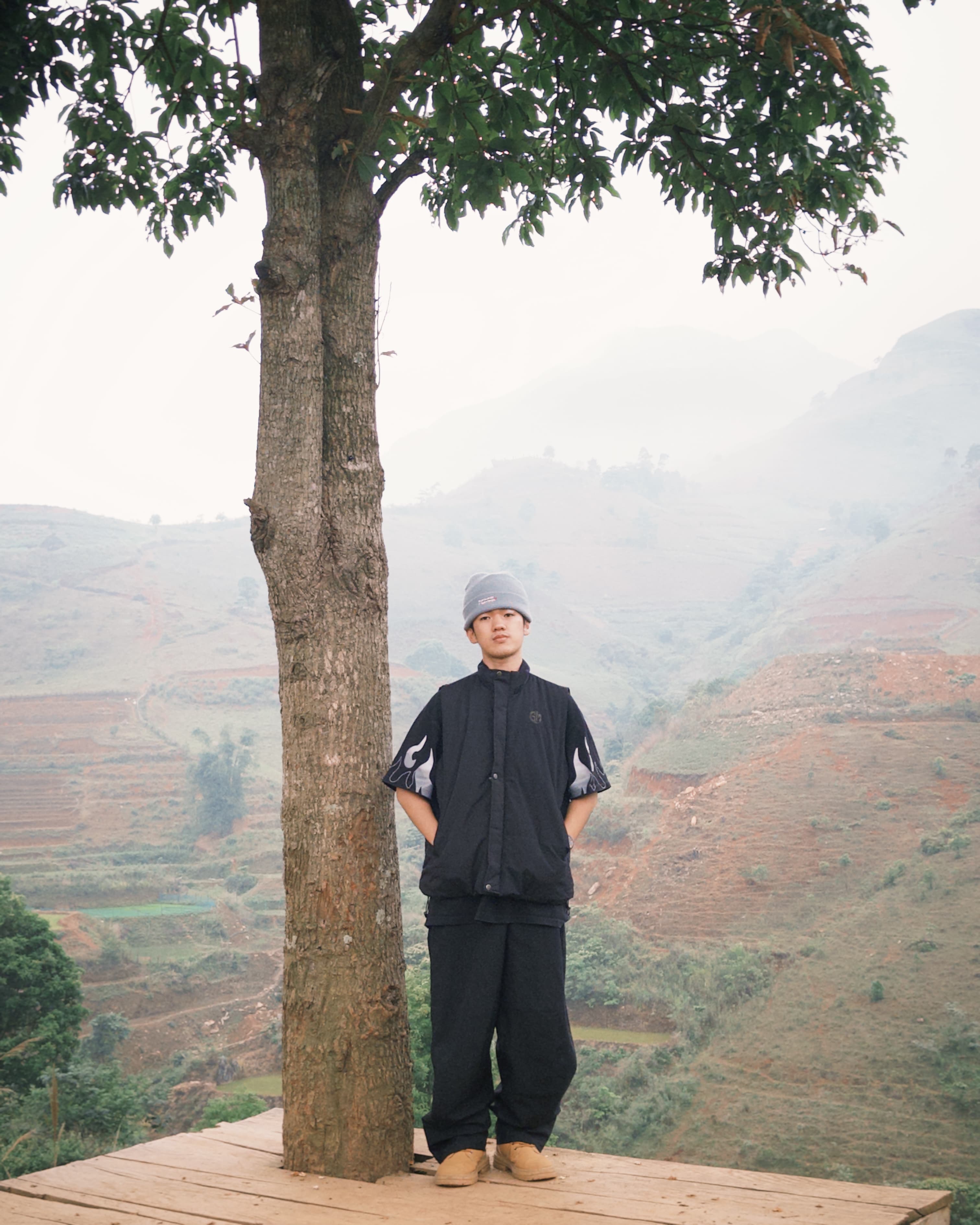 Son Hoang standing on a wooden platform with terraced mountains behind him